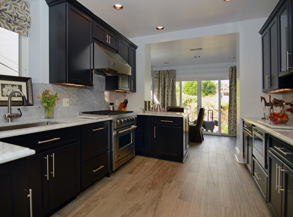 Example of a mid-sized trendy galley light wood floor eat-in kitchen design in DC Metro with an undermount sink, dark wood cabinets, granite countertops, white backsplash and stainless steel appliances
