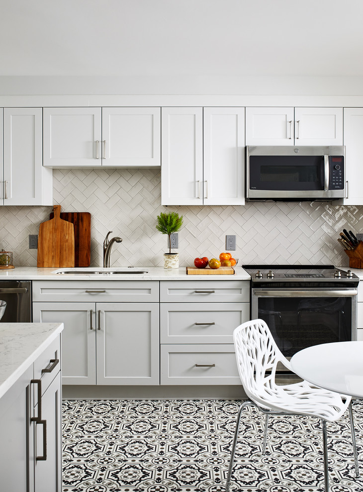 Inredning av ett klassiskt vit vitt kök och matrum, med en dubbel diskho, skåp i shakerstil, vita skåp, beige stänkskydd, rostfria vitvaror, flerfärgat golv och vinylgolv