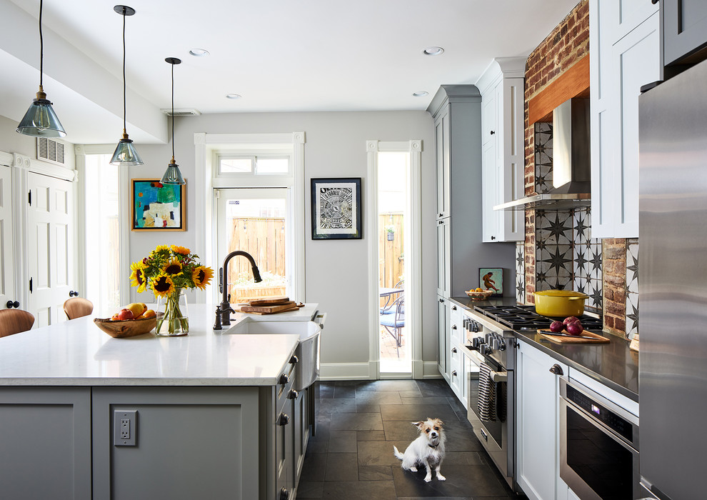 Imagen de cocina comedor lineal ecléctica de tamaño medio con puertas de armario grises, electrodomésticos de acero inoxidable, una isla, suelo gris y encimeras blancas