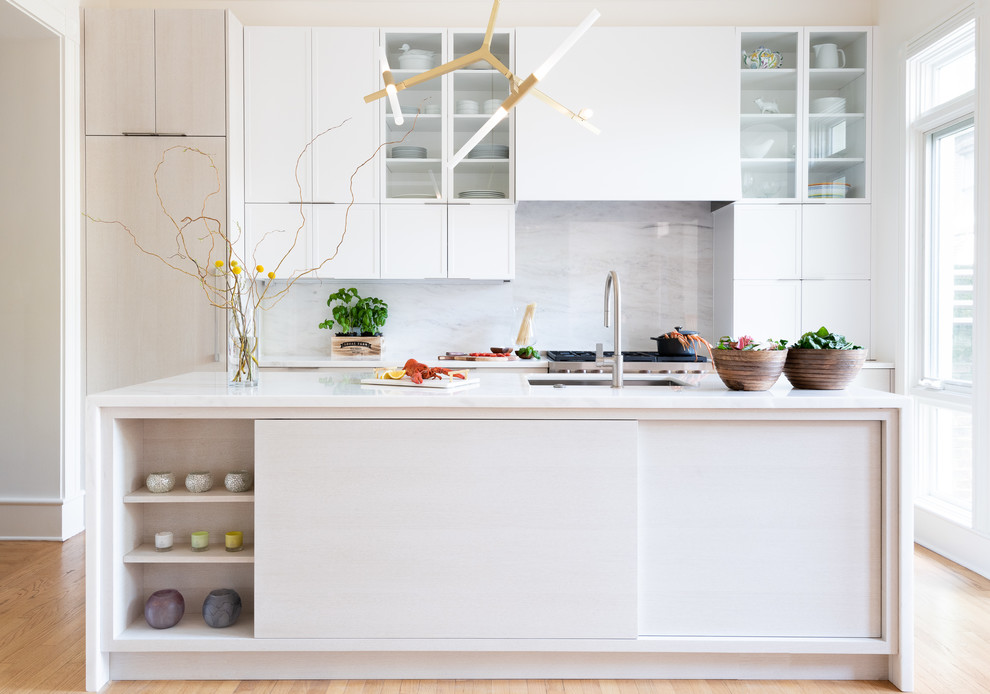 Modern inredning av ett mellanstort vit linjärt vitt kök, med en undermonterad diskho, skåp i shakerstil, vita skåp, marmorbänkskiva, vitt stänkskydd, stänkskydd i marmor, rostfria vitvaror, ljust trägolv, en köksö och brunt golv