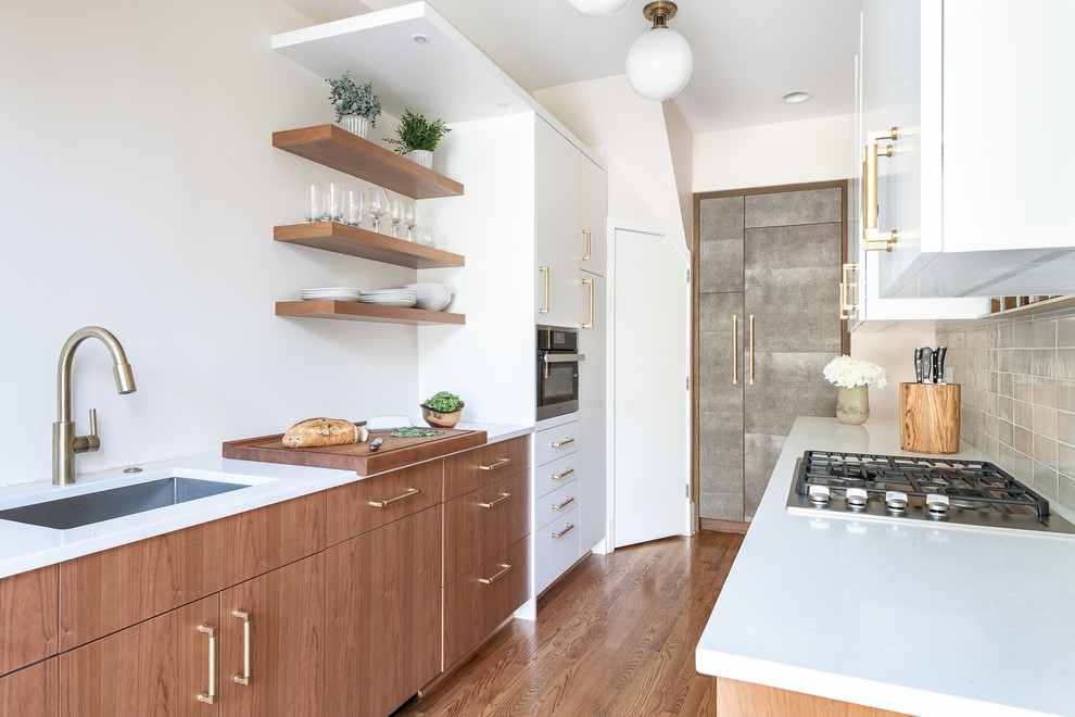 This is an example of a medium sized midcentury galley kitchen pantry in DC Metro with a submerged sink, flat-panel cabinets, medium wood cabinets, quartz worktops, white splashback, porcelain splashback, stainless steel appliances, medium hardwood flooring, no island, brown floors and white worktops.