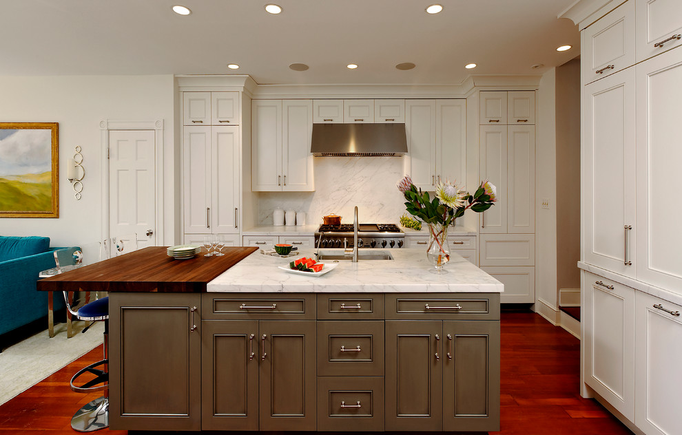 Medium sized traditional l-shaped open plan kitchen in DC Metro with a submerged sink, white cabinets, white splashback, stainless steel appliances, medium hardwood flooring, an island, wood worktops, stone tiled splashback and recessed-panel cabinets.