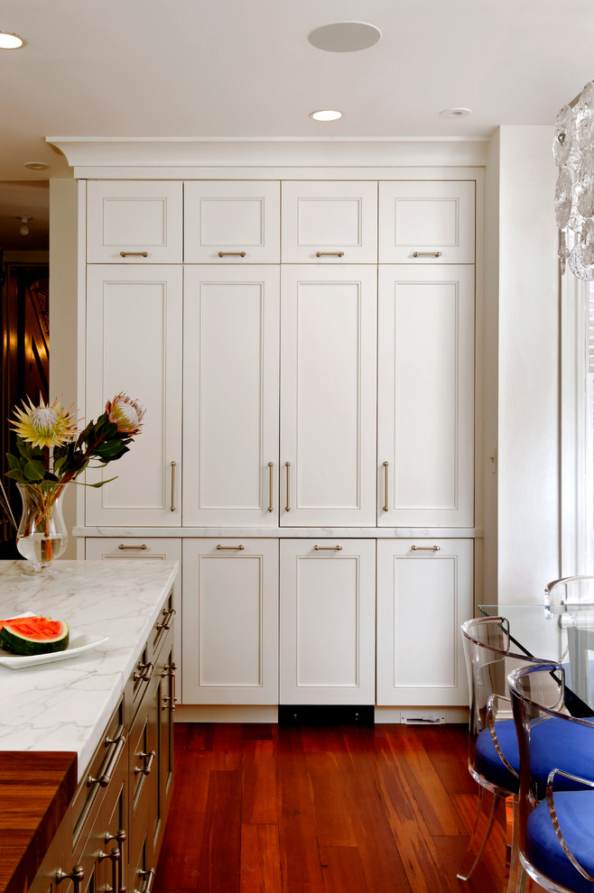 Inredning av ett klassiskt mellanstort kök, med en undermonterad diskho, vita skåp, träbänkskiva, vitt stänkskydd, rostfria vitvaror, mellanmörkt trägolv, en köksö, luckor med lamellpanel och stänkskydd i stenkakel