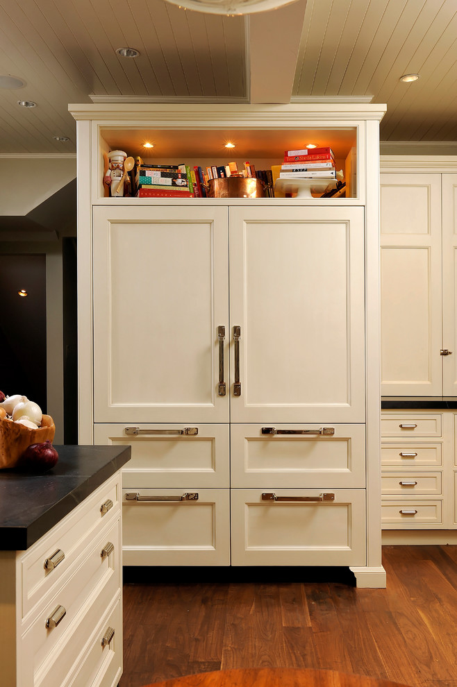 Foto på ett mellanstort vintage kök, med en undermonterad diskho, luckor med profilerade fronter, vita skåp, rostfria vitvaror, mellanmörkt trägolv, bänkskiva i täljsten, rött stänkskydd, stänkskydd i tegel och brunt golv