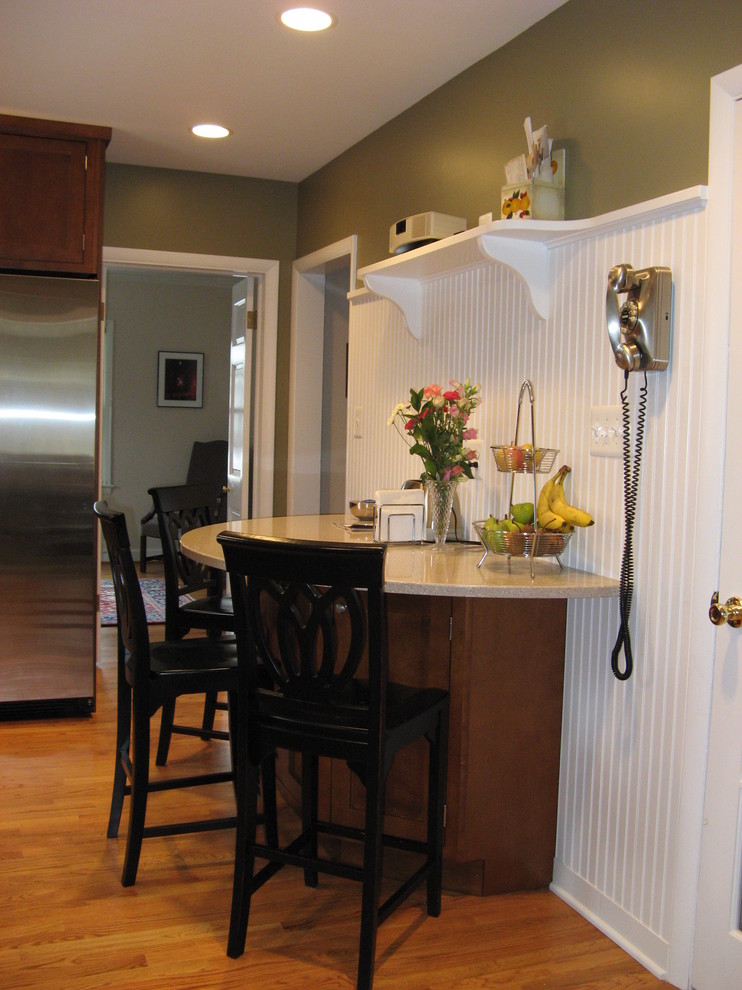 ワシントンD.C.にある小さなトラディショナルスタイルのおしゃれなキッチン (アンダーカウンターシンク、シェーカースタイル扉のキャビネット、中間色木目調キャビネット、クオーツストーンカウンター、白いキッチンパネル、シルバーの調理設備、淡色無垢フローリング) の写真