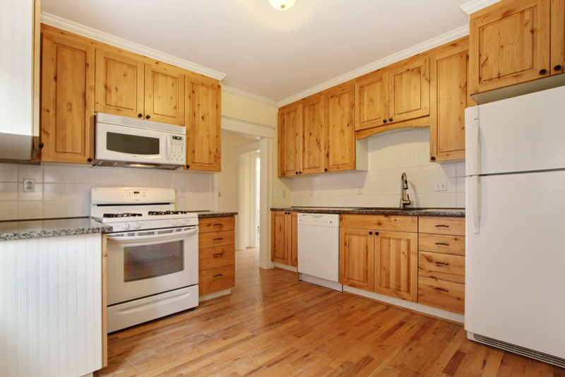 Cette photo montre une petite cuisine américaine chic en bois brun avec un plan de travail en granite, une crédence blanche, une crédence en céramique, un électroménager blanc, un sol en bois brun et aucun îlot.