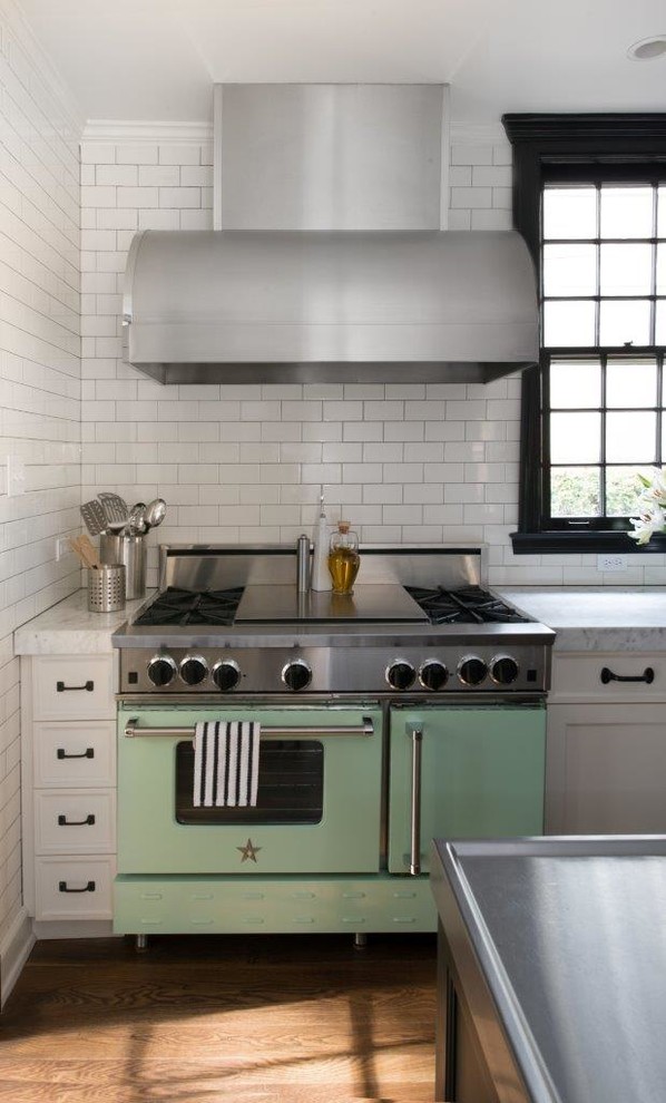 Geschlossene Klassische Küche mit Küchenrückwand in Weiß, Rückwand aus Metrofliesen, bunten Elektrogeräten, braunem Holzboden und Kücheninsel in Chicago