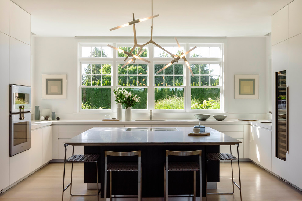 Immagine di una cucina design con lavello sottopiano, ante lisce, ante bianche, paraspruzzi bianco, parquet chiaro, pavimento beige e top bianco