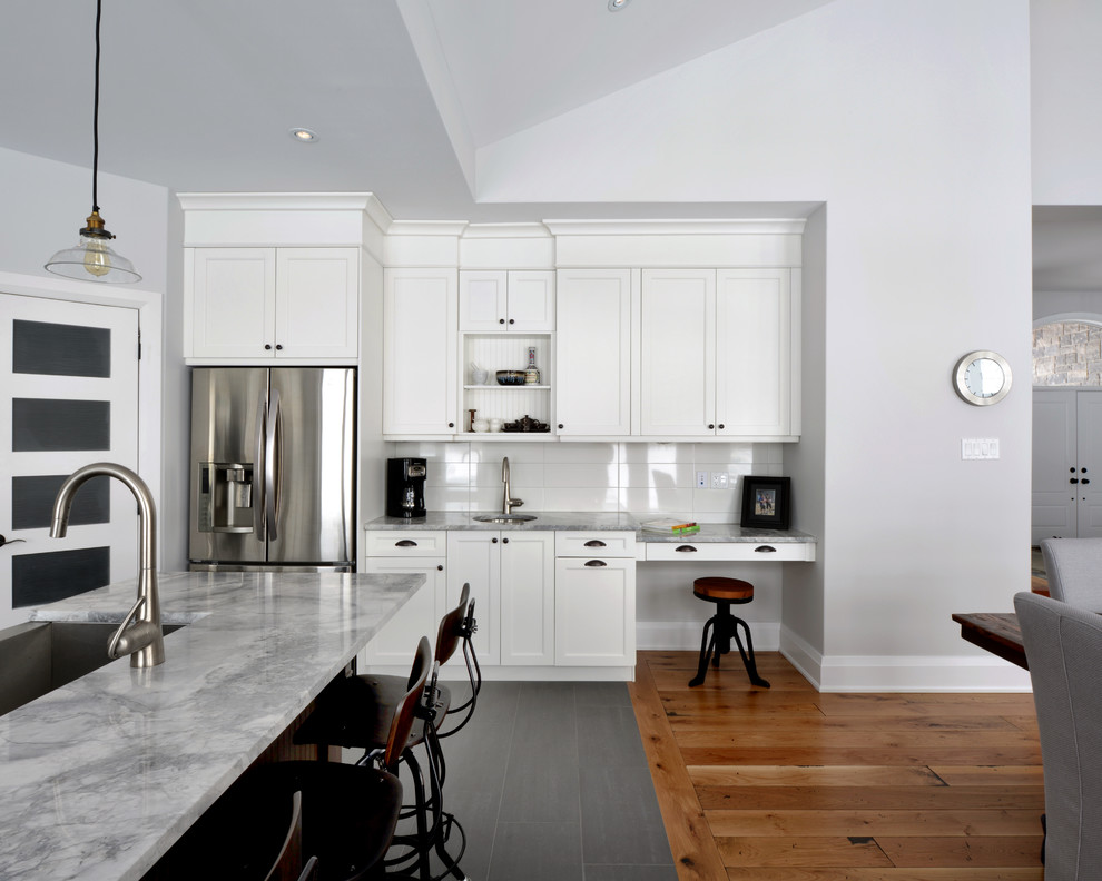 Diseño de cocina actual con electrodomésticos de acero inoxidable, encimera de granito, armarios estilo shaker, puertas de armario blancas y salpicadero blanco