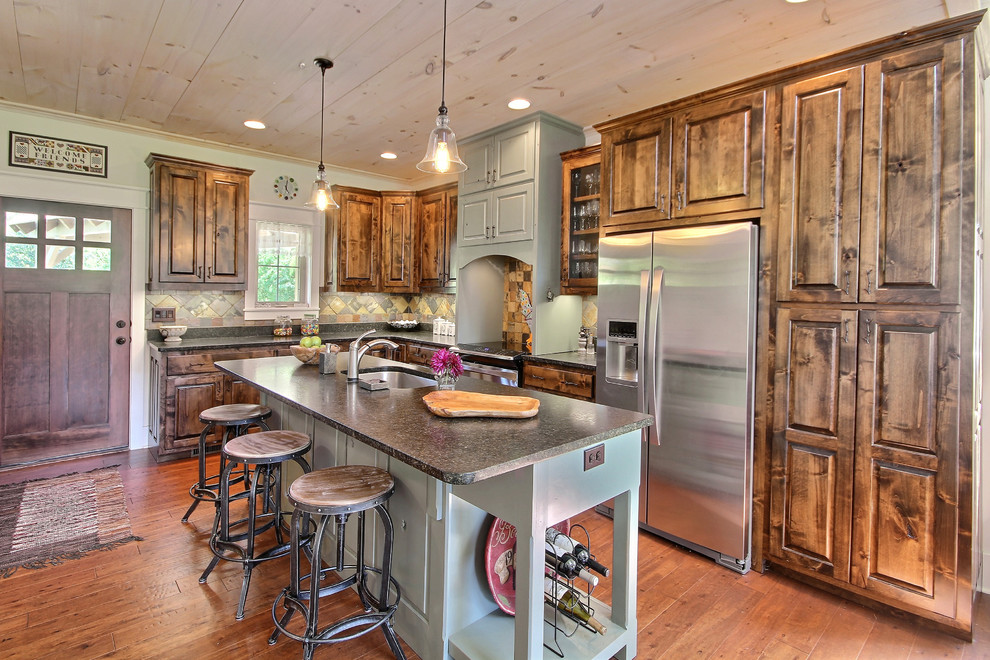 Inredning av ett lantligt mellanstort brun brunt kök, med en undermonterad diskho, luckor med upphöjd panel, skåp i mellenmörkt trä, granitbänkskiva, beige stänkskydd, rostfria vitvaror, mellanmörkt trägolv, en köksö och brunt golv
