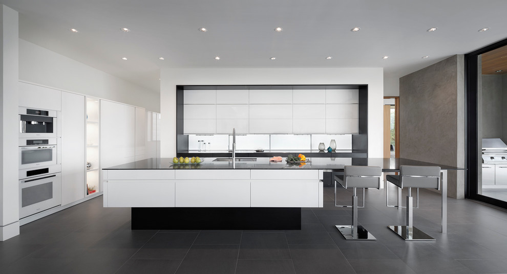 Esempio di una cucina minimal con lavello a doppia vasca, ante lisce, ante bianche, top in quarzite, elettrodomestici bianchi, pavimento in gres porcellanato, paraspruzzi bianco e pavimento nero