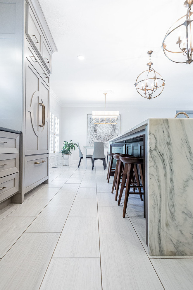 Example of a large minimalist u-shaped porcelain tile and gray floor kitchen design in Other with a farmhouse sink, gray cabinets, marble countertops, gray backsplash, marble backsplash, stainless steel appliances, an island and multicolored countertops