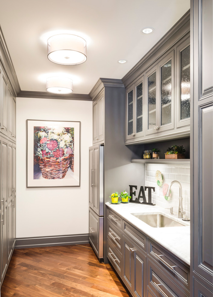 Klassische Küche mit Waschbecken, Kassettenfronten, grauen Schränken, Granit-Arbeitsplatte, Küchenrückwand in Weiß, Rückwand aus Metrofliesen und dunklem Holzboden in Cleveland