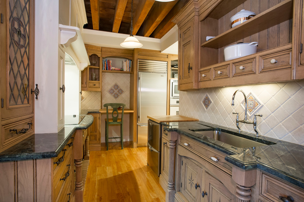Modelo de cocina tradicional con fregadero bajoencimera, puertas de armario de madera oscura, salpicadero beige y electrodomésticos de acero inoxidable