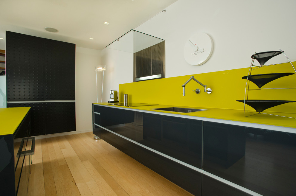 Moderne Küche mit Unterbauwaschbecken, flächenbündigen Schrankfronten, schwarzen Schränken, Küchenrückwand in Gelb, Elektrogeräten mit Frontblende und gelber Arbeitsplatte in Boston