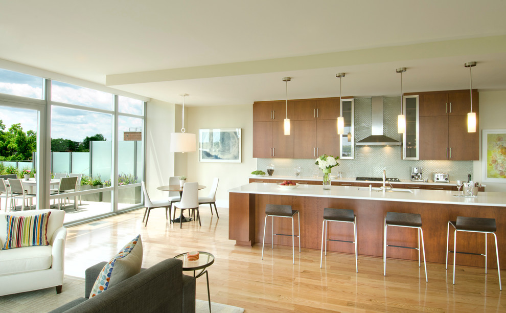 Cette image montre une cuisine ouverte parallèle design en bois brun avec un placard à porte plane, parquet clair et îlot.