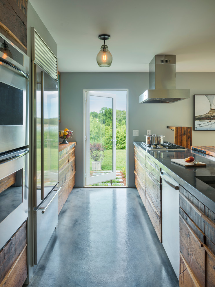 Photo of a contemporary galley kitchen in Providence with distressed cabinets, stainless steel appliances, concrete flooring and a breakfast bar.
