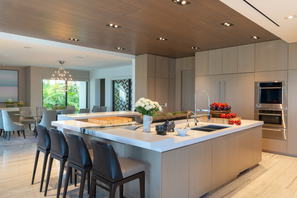 Photo of an expansive contemporary kitchen/diner in Miami with flat-panel cabinets, stainless steel appliances, marble flooring, an island, a double-bowl sink, brown cabinets and white worktops.