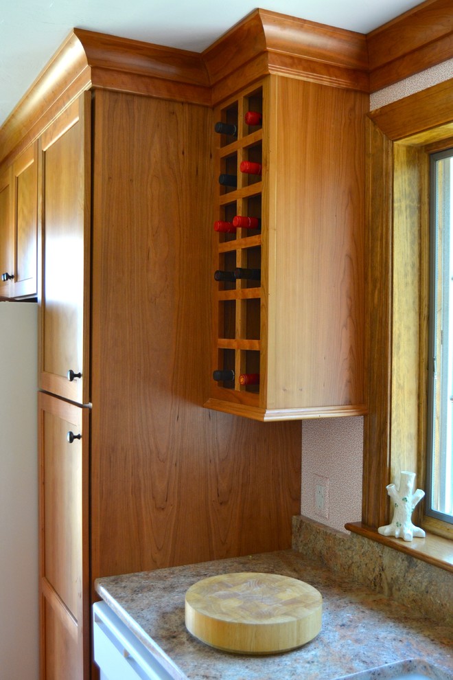 ボストンにある小さなトランジショナルスタイルのおしゃれなキッチン (シングルシンク、フラットパネル扉のキャビネット、中間色木目調キャビネット、御影石カウンター、白い調理設備、無垢フローリング) の写真