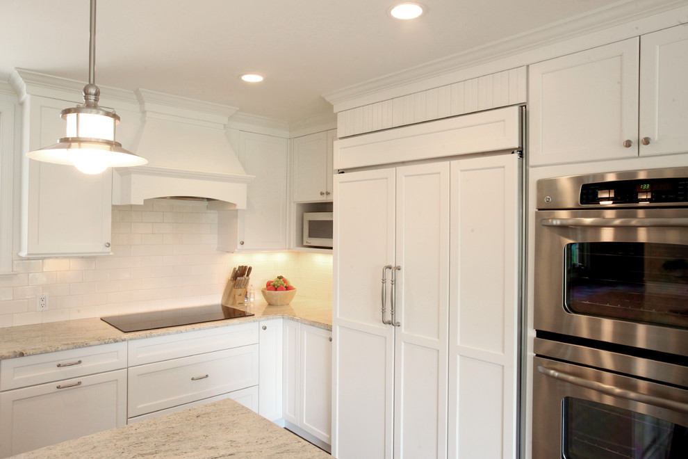 Kitchen - mid-sized traditional u-shaped medium tone wood floor kitchen idea in New York with an undermount sink, recessed-panel cabinets, white cabinets, granite countertops, white backsplash, ceramic backsplash, paneled appliances and an island