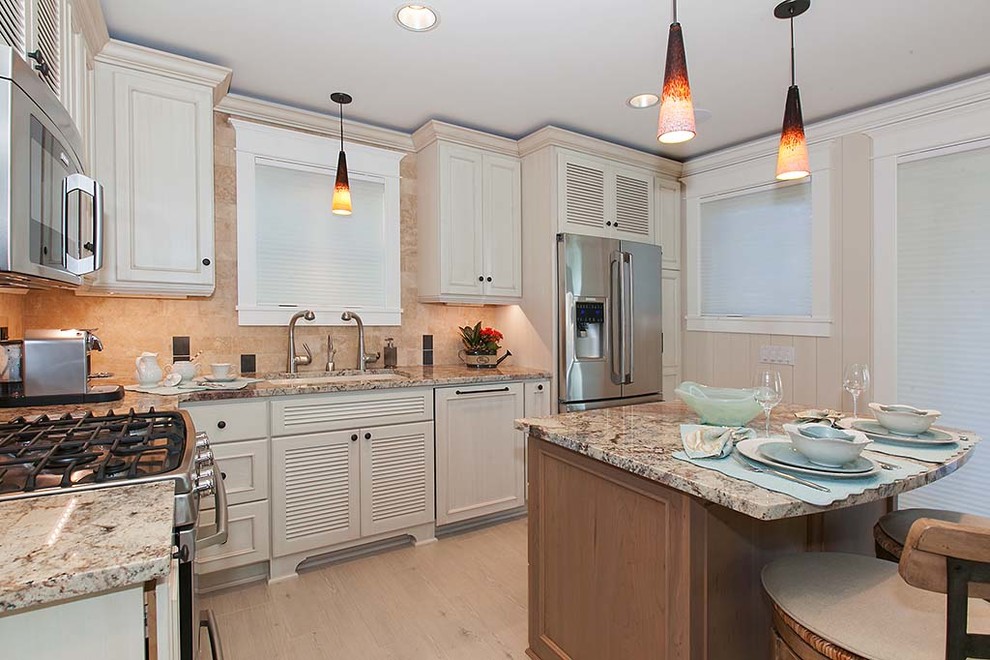 Small beach style l-shaped porcelain tile open concept kitchen photo in Seattle with an undermount sink, louvered cabinets, white cabinets, granite countertops, beige backsplash, stone tile backsplash, stainless steel appliances and an island