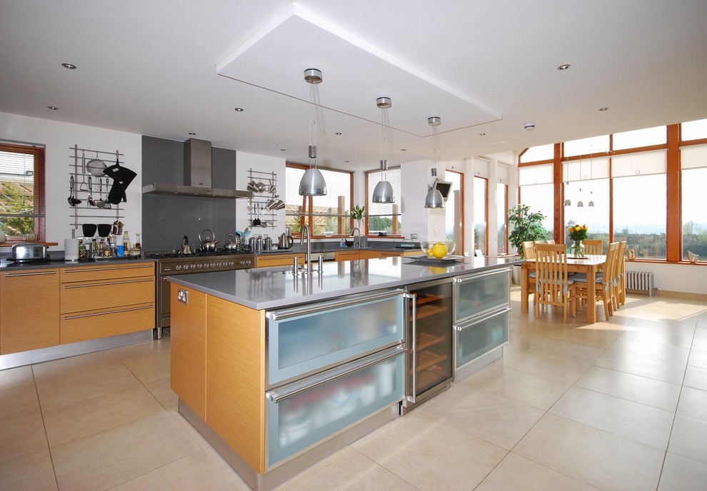 Moderne Wohnküche mit flächenbündigen Schrankfronten, hellen Holzschränken, Küchengeräten aus Edelstahl und Kücheninsel in Sonstige