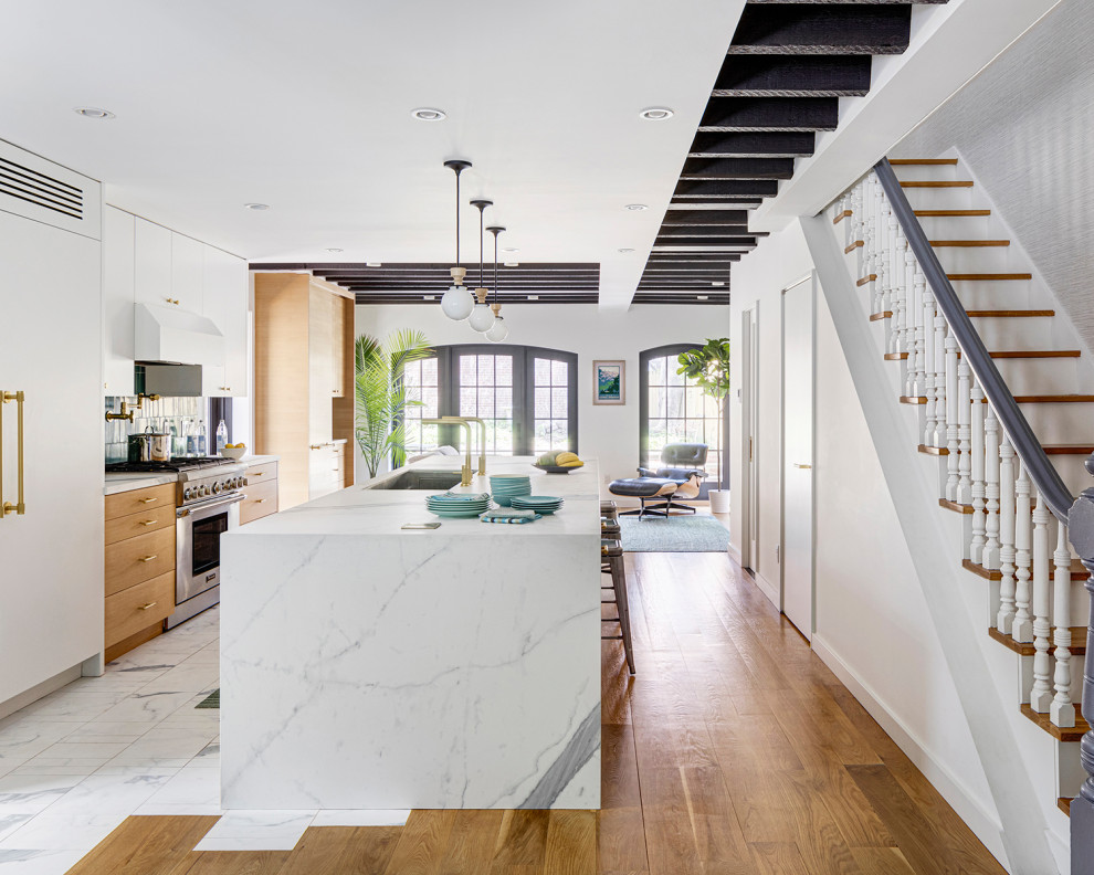 Foto di un cucina con isola centrale minimalista con lavello sottopiano, ante lisce, paraspruzzi verde, elettrodomestici bianchi e pavimento in legno massello medio