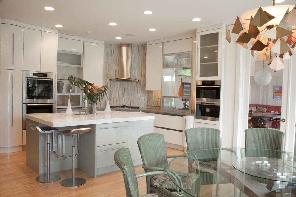 Moderne Wohnküche mit flächenbündigen Schrankfronten, weißen Schränken, bunter Rückwand, Rückwand aus Stäbchenfliesen und Küchengeräten aus Edelstahl in New York