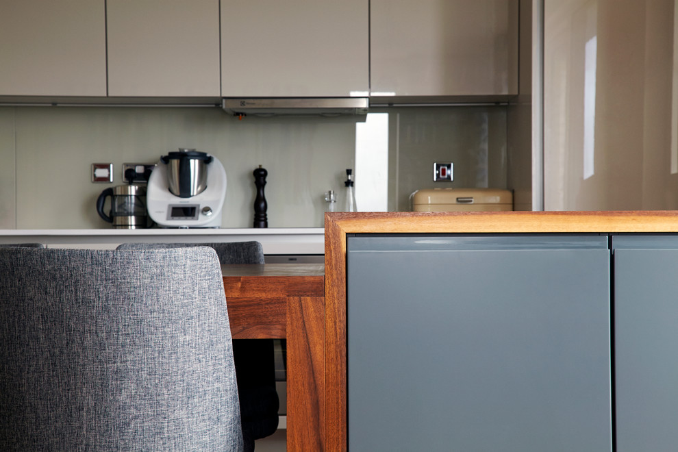 Esempio di una cucina minimalista di medie dimensioni con lavello da incasso, ante lisce, ante grigie, paraspruzzi grigio, paraspruzzi con lastra di vetro, elettrodomestici in acciaio inossidabile e parquet scuro