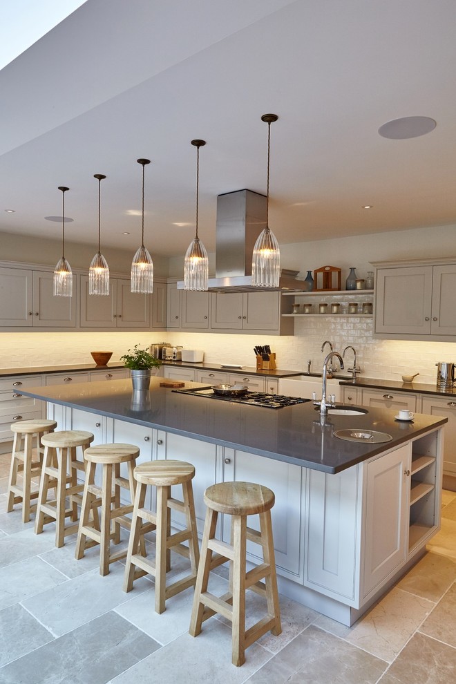Design ideas for a large classic grey and cream u-shaped kitchen/diner in Devon with a belfast sink, beaded cabinets, grey cabinets, composite countertops, white splashback, metro tiled splashback, integrated appliances, limestone flooring, an island, beige floors, grey worktops and a drop ceiling.