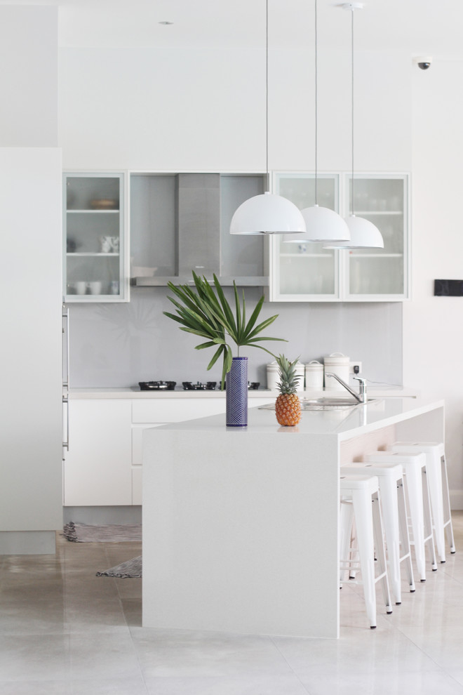 Esempio di un cucina con isola centrale minimal con ante di vetro, ante bianche, paraspruzzi grigio e paraspruzzi con lastra di vetro