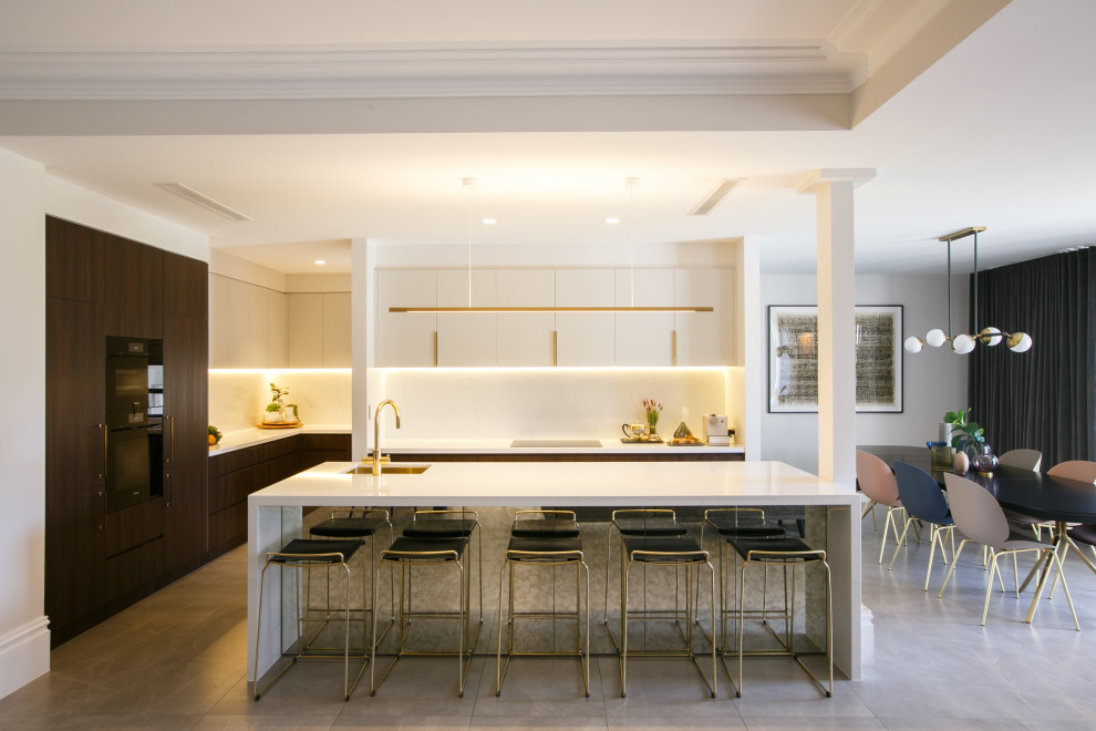 This is an example of a contemporary l-shaped kitchen/diner in Sydney with a submerged sink, flat-panel cabinets, white cabinets, white splashback, an island, grey floors, white worktops and a drop ceiling.