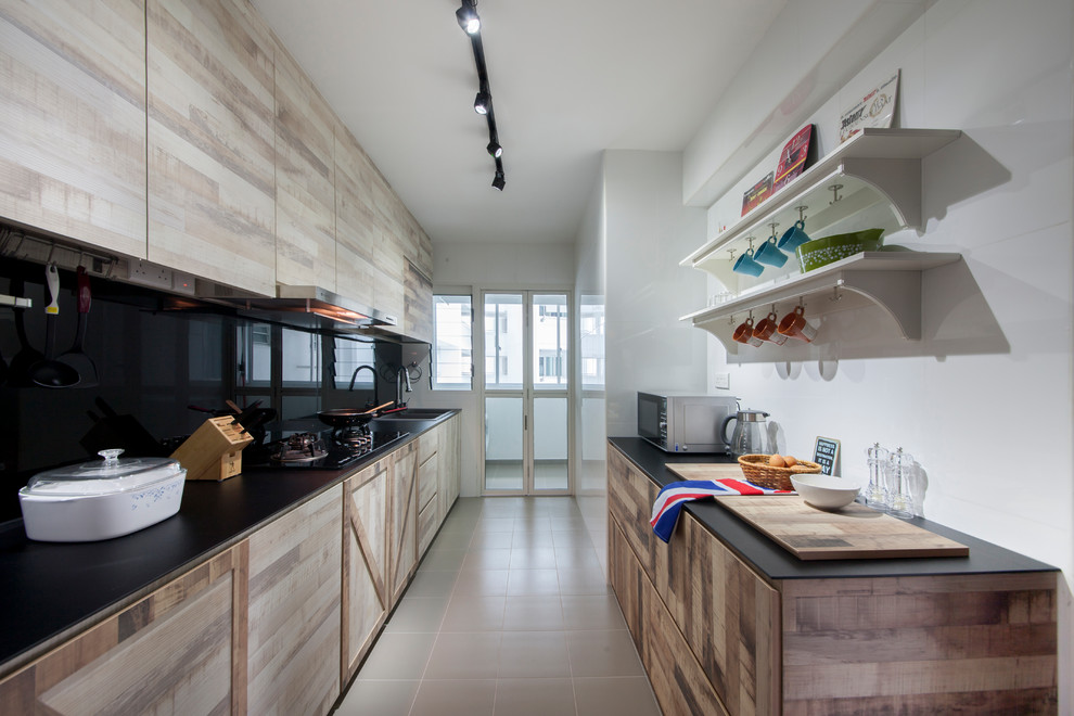 Immagine di una cucina parallela chic con lavello da incasso, ante lisce, ante in legno chiaro, paraspruzzi nero, elettrodomestici da incasso, pavimento beige e top nero
