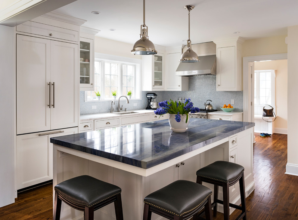 Example of a mid-sized classic l-shaped medium tone wood floor open concept kitchen design in New York with an undermount sink, shaker cabinets, white cabinets, quartzite countertops, blue backsplash, mosaic tile backsplash, paneled appliances and an island