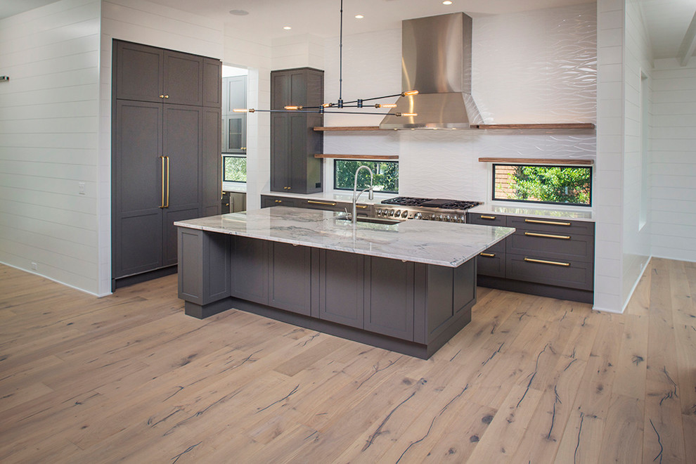 Inspiration for a large contemporary l-shaped light wood floor open concept kitchen remodel in Charleston with an undermount sink, shaker cabinets, gray cabinets, marble countertops, white backsplash, porcelain backsplash, stainless steel appliances and an island