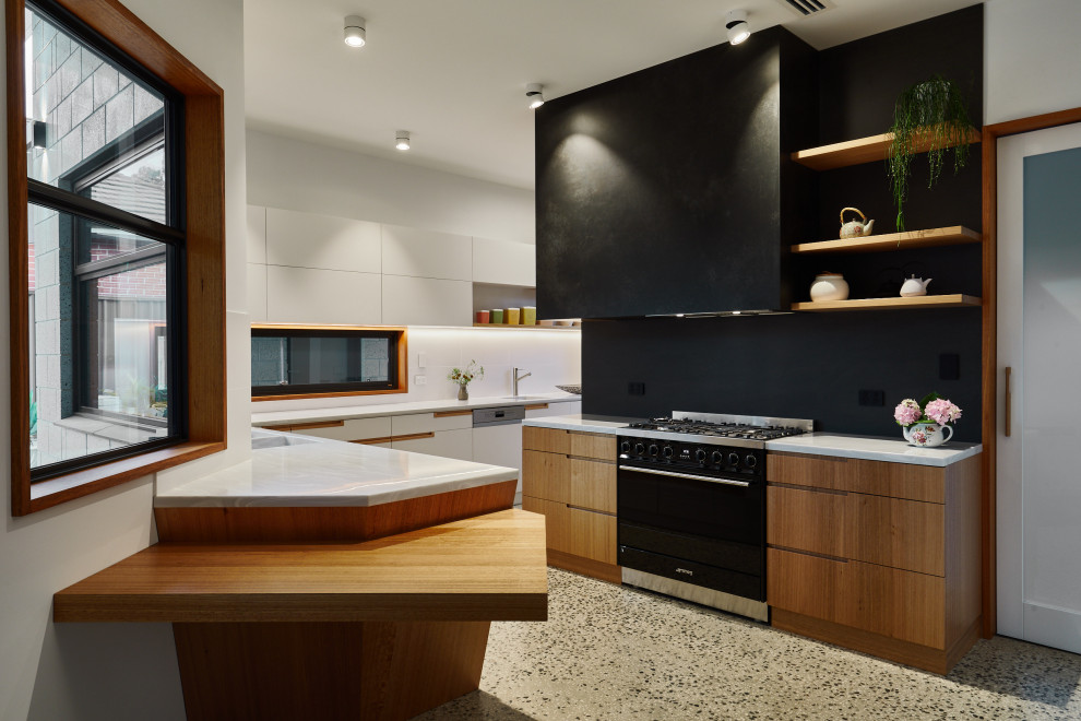Design ideas for a large contemporary l-shaped kitchen in Adelaide with flat-panel cabinets, medium wood cabinets, white splashback, terrazzo flooring, a breakfast bar, grey floors, white worktops, a belfast sink, composite countertops, ceramic splashback and black appliances.