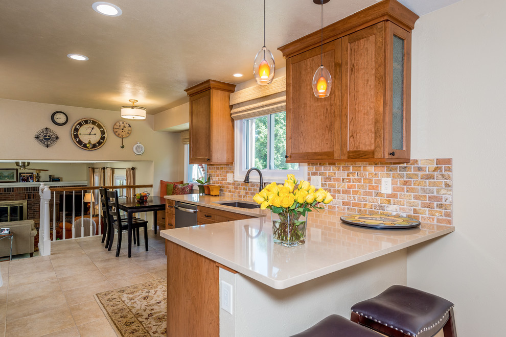 Eat-in kitchen - mid-sized traditional l-shaped porcelain tile eat-in kitchen idea in Denver with an undermount sink, shaker cabinets, medium tone wood cabinets, glass countertops, multicolored backsplash, stone tile backsplash, colored appliances and a peninsula