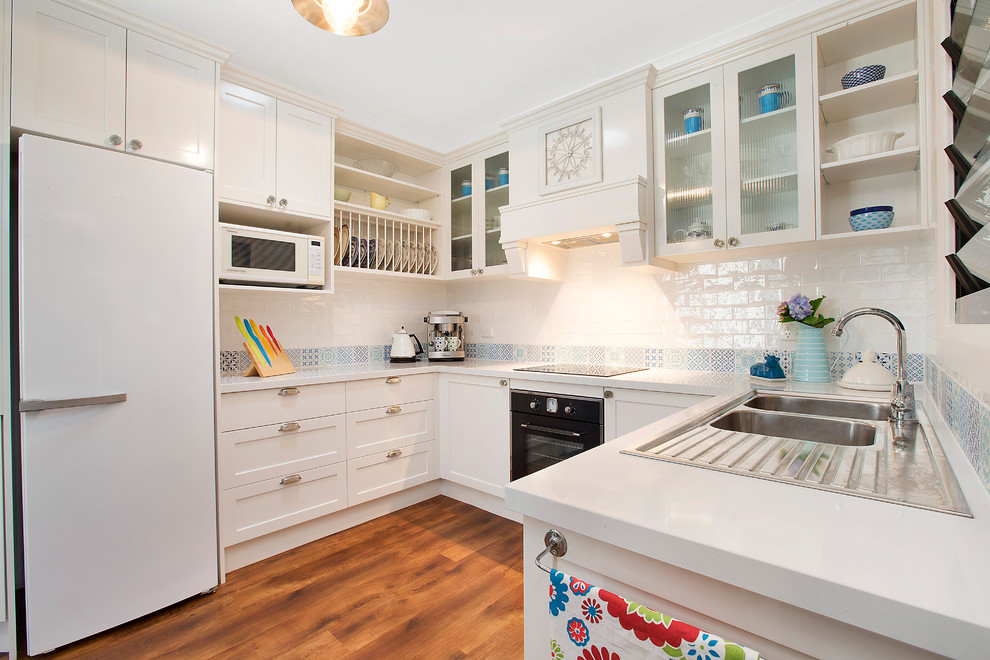 Klassische Küche ohne Insel in U-Form mit Einbauwaschbecken, Schrankfronten im Shaker-Stil, weißen Schränken, Küchenrückwand in Blau und dunklem Holzboden in Sydney