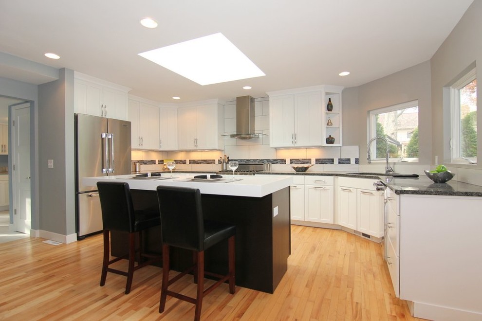 Inspiration for a large contemporary u-shaped light wood floor eat-in kitchen remodel in Wichita with an undermount sink, shaker cabinets, white cabinets, granite countertops, white backsplash, porcelain backsplash, stainless steel appliances and an island
