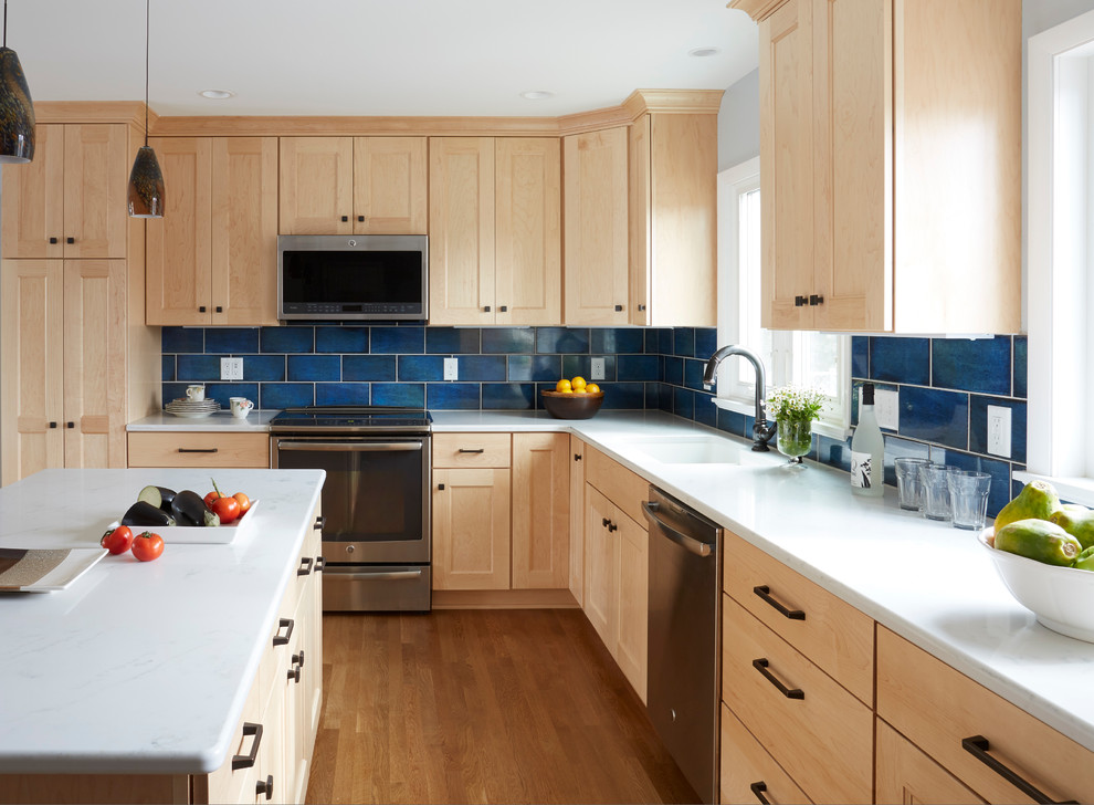 Mid-sized transitional l-shaped medium tone wood floor eat-in kitchen photo in Milwaukee with an undermount sink, shaker cabinets, light wood cabinets, quartzite countertops, blue backsplash, ceramic backsplash, stainless steel appliances and an island