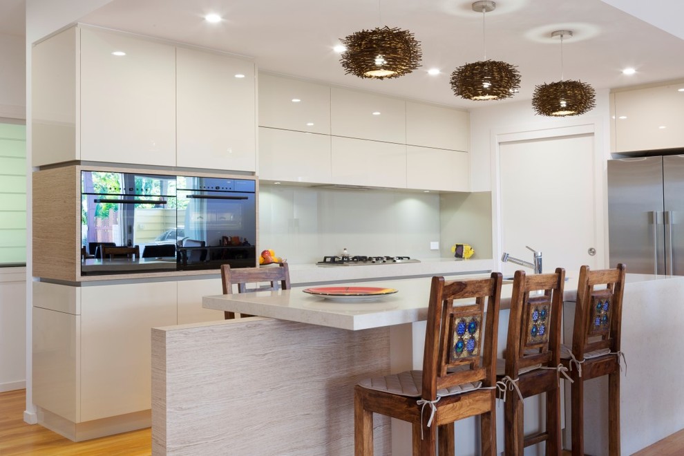 Moderne Küche mit Unterbauwaschbecken, flächenbündigen Schrankfronten, weißen Schränken, Küchenrückwand in Weiß und Küchengeräten aus Edelstahl in Brisbane