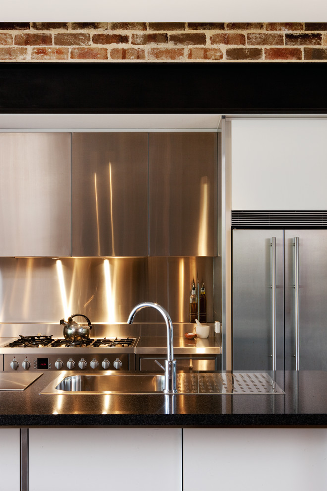 Idéer för ett modernt kök, med en nedsänkt diskho, släta luckor, skåp i rostfritt stål, bänkskiva i rostfritt stål, stänkskydd med metallisk yta, rostfria vitvaror och en köksö