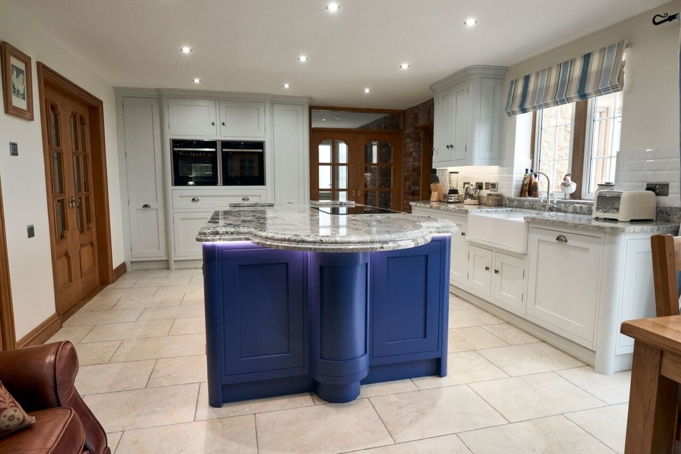 Exempel på ett stort modernt kök och matrum, med en rustik diskho, skåp i shakerstil, grå skåp, granitbänkskiva, vitt stänkskydd, stänkskydd i keramik, rostfria vitvaror, travertin golv och en köksö