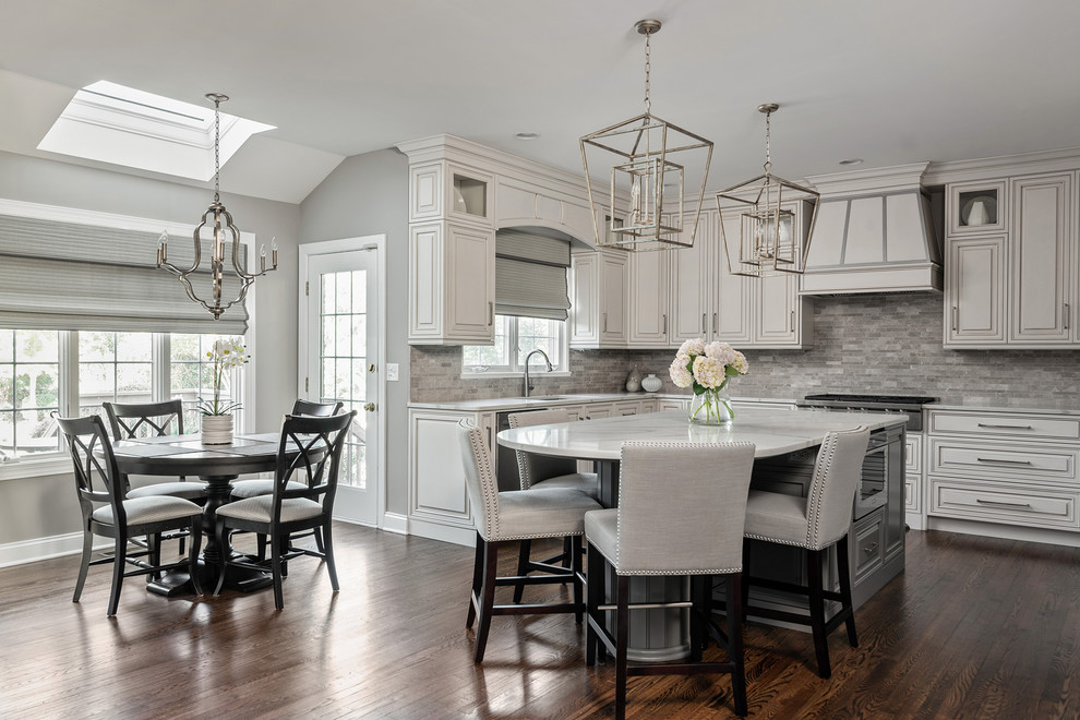 Example of a large classic u-shaped dark wood floor and brown floor eat-in kitchen design in Charlotte with an undermount sink, raised-panel cabinets, white cabinets, quartz countertops, gray backsplash, stone tile backsplash, stainless steel appliances, an island and gray countertops