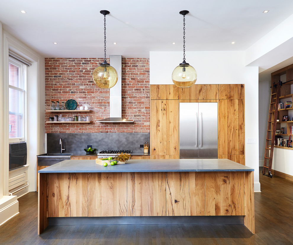 Bild på ett kök, med en enkel diskho, släta luckor, skåp i slitet trä, marmorbänkskiva, stänkskydd med metallisk yta, stänkskydd i tegel, rostfria vitvaror, mellanmörkt trägolv och en köksö