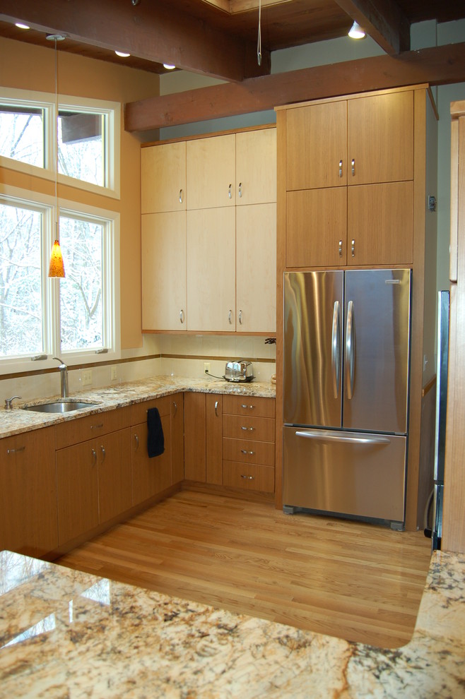 Exempel på ett stort modernt kök och matrum, med en undermonterad diskho, släta luckor, skåp i ljust trä, granitbänkskiva, beige stänkskydd, stänkskydd i keramik, rostfria vitvaror och ljust trägolv