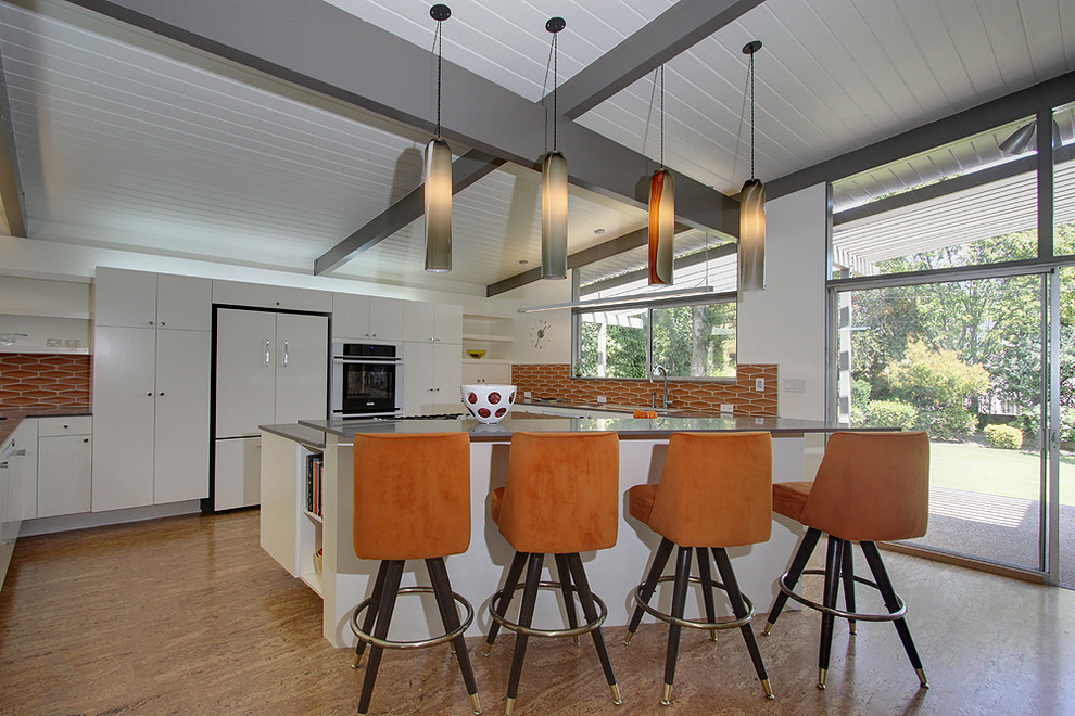 Exemple d'une cuisine encastrable moderne en U avec un placard à porte plane, des portes de placard blanches et une crédence orange.