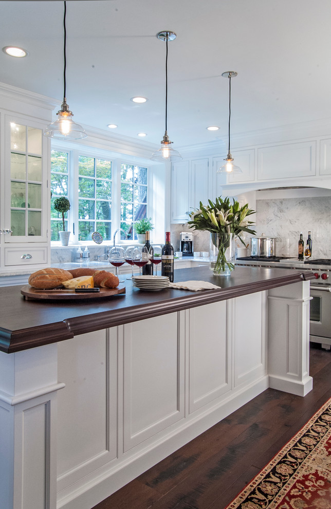 Eat-in kitchen - large traditional l-shaped dark wood floor eat-in kitchen idea in Philadelphia with an undermount sink, flat-panel cabinets, white cabinets, wood countertops, white backsplash, stone tile backsplash, stainless steel appliances and an island