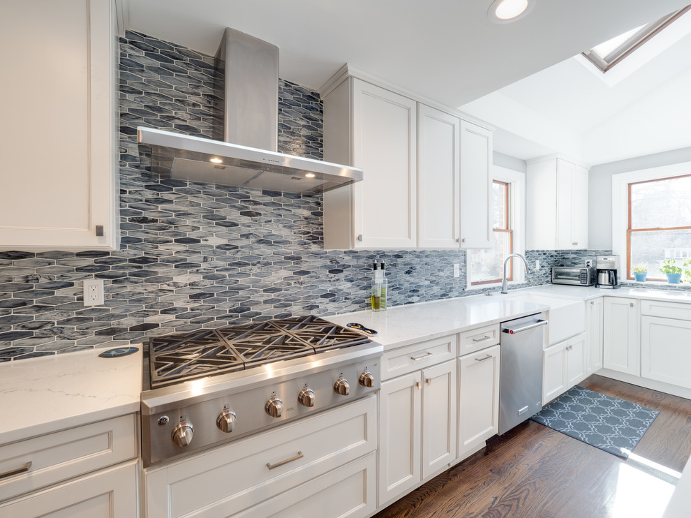 Large transitional l-shaped dark wood floor and brown floor open concept kitchen photo in Philadelphia with a farmhouse sink, flat-panel cabinets, white cabinets, blue backsplash, stainless steel appliances, an island, quartz countertops and marble backsplash