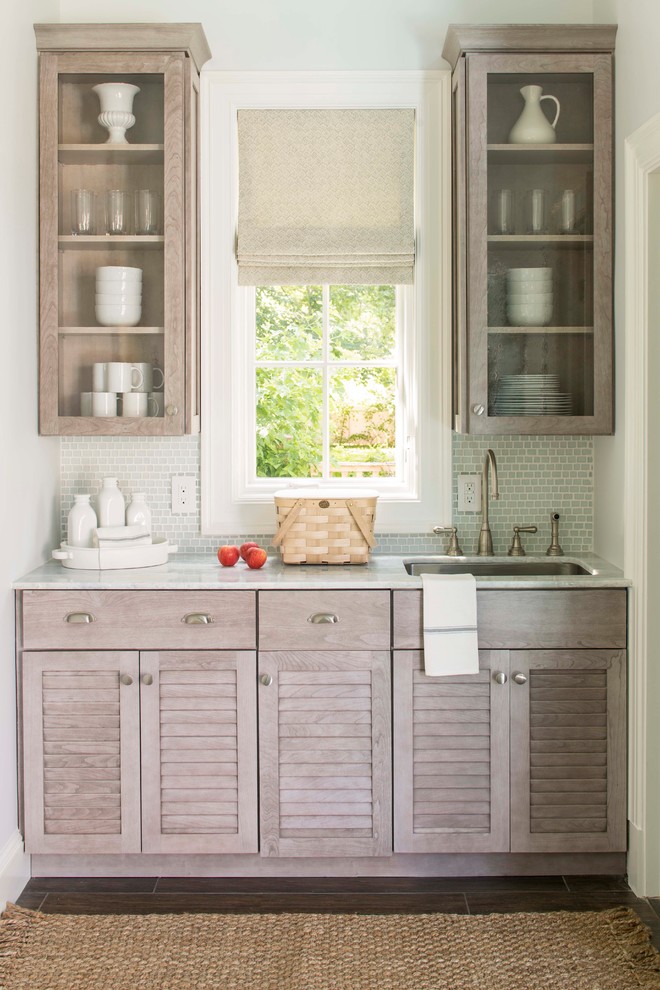 ワシントンD.C.にあるトラディショナルスタイルのおしゃれなII型キッチン (ルーバー扉のキャビネット、グレーのキャビネット、白いキッチンパネル、サブウェイタイルのキッチンパネル、シルバーの調理設備、茶色い床) の写真